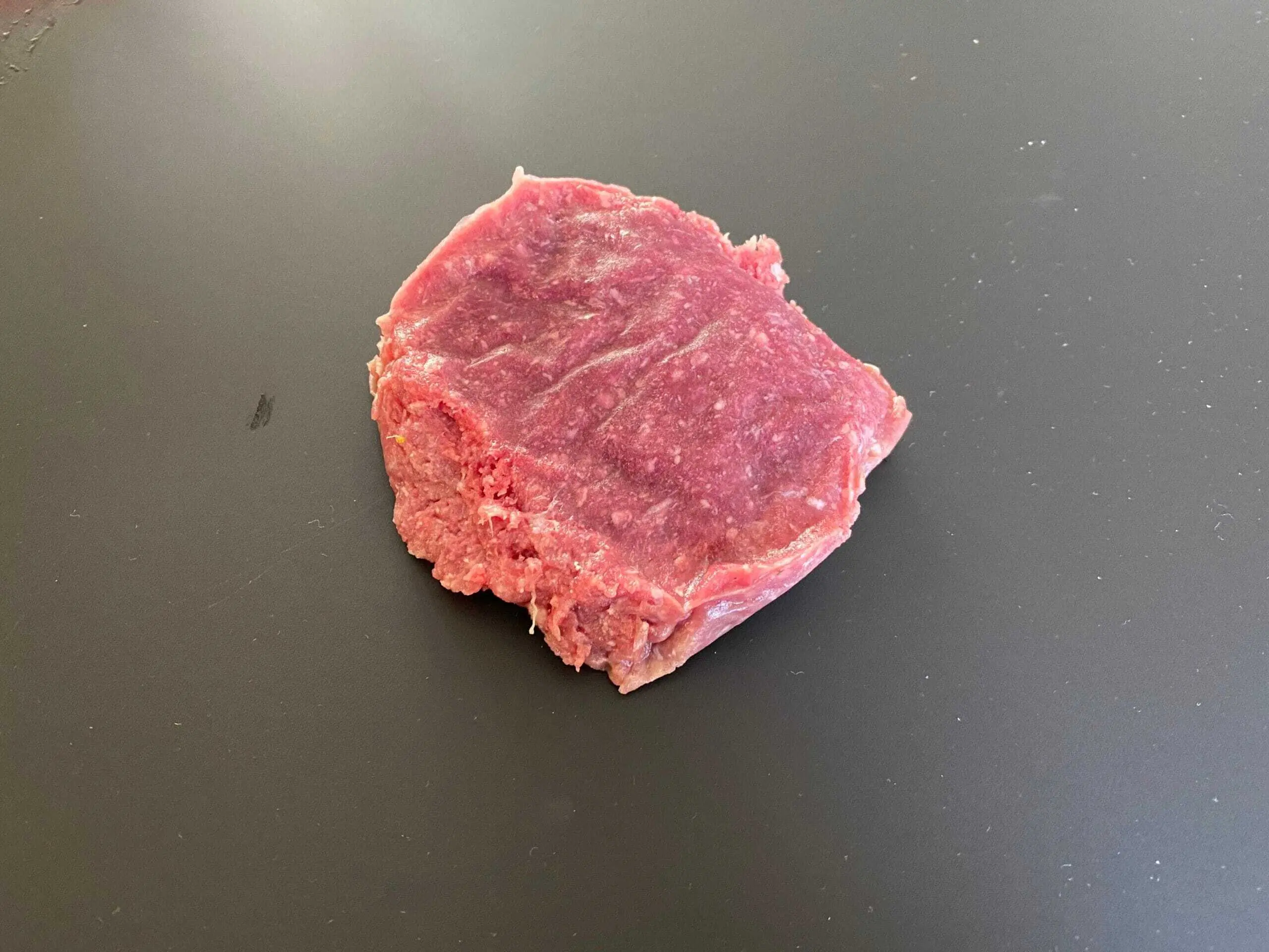 Grasgevoerde tartaar steak uit de verpakking gehaald en ligt opm het aanrecht klaar voor de bereiding.